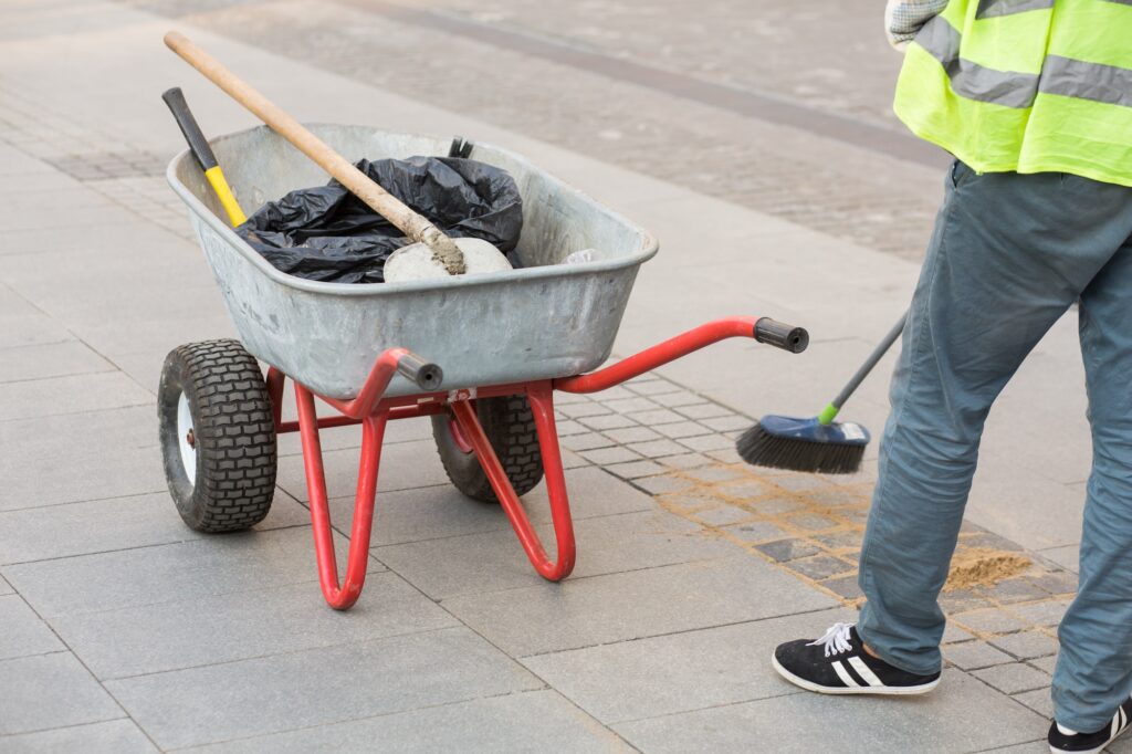 Road cleaning. The man is sweeping the sidewalk. City worker. Brick Road Cleaning by Pro